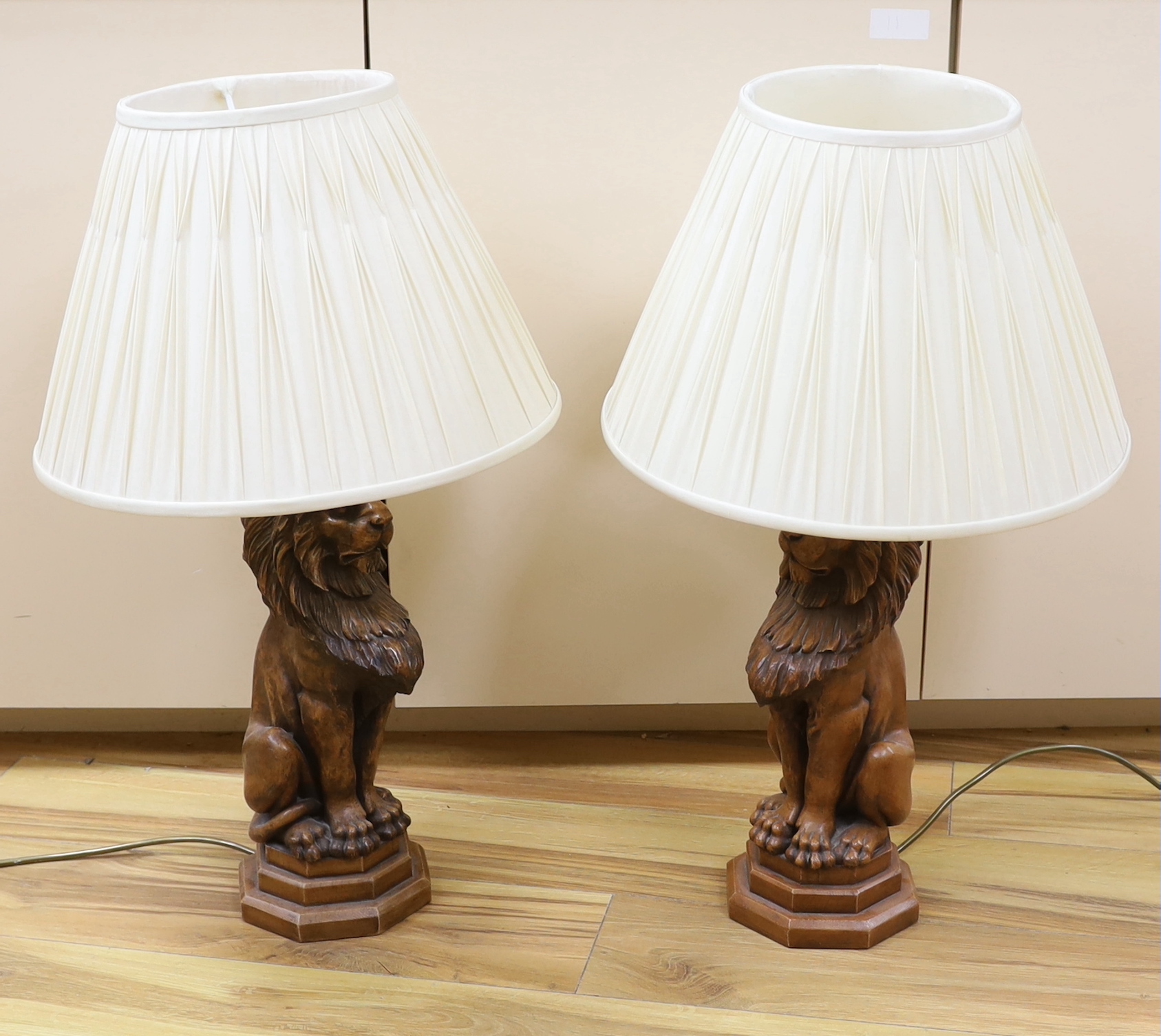 A pair of faux carved lion table lamps, 65cm high including shades